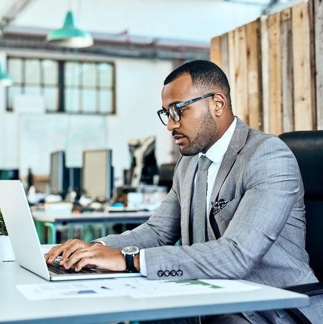 Accounting professional reviewing financial work on a laptop in a modern office.
