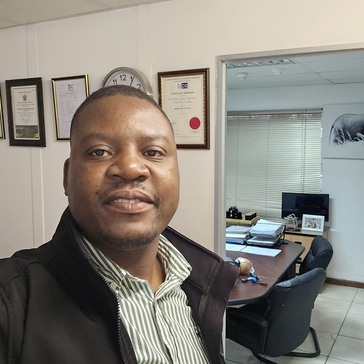 Double Pillars team member photographed in an office beside framed certificates.